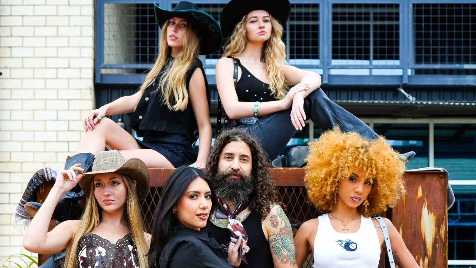 Group of people posing outdoors with a rustic background